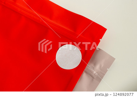 White circular sticker on red poly mailer envelope with natural shadow. White circular sticker on red poly mailer envelope with natural shadow. 124892077