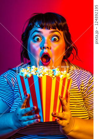 A woman holding a box of popcorn in front of her face A woman holding a box of popcorn in front of her face 124892195