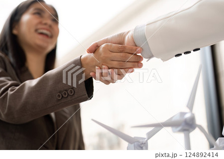 Business Collaboration and Sustainability. A woman enthusiastically shaking hands to solidify a partnership focused on sustainable practices. 124892414