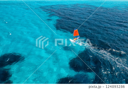 Aerial view of windsurfer on blue sea at sunny summer day Aerial view of windsurfer on blue sea at sunny summer day 124893286