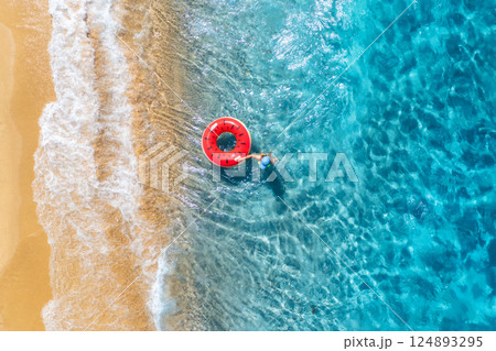 Aerial view of a young woman swimming with red swim ring 124893295