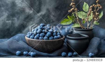 Bountiful blueberries in a black bowl with dried flowers on a dark surface 124893919