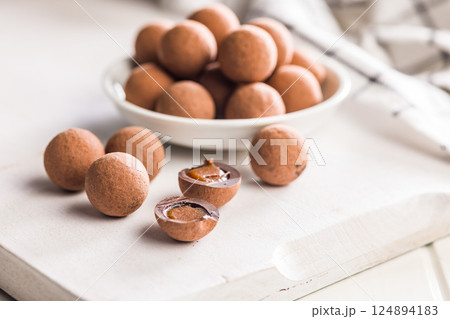 Chocolate truffles with cocoa powder and caramel filling on kitchen table. Chocolate truffles with cocoa powder and caramel filling on kitchen table. 124894183