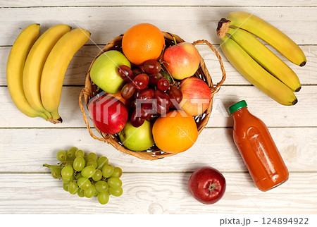 Healthy vegan products for healthy lifestyle. Grapes, oranges, pineapple, apples, bananas and natural juice on wooden background, detox diet and weight loss concept, shop advertisement. 124894922