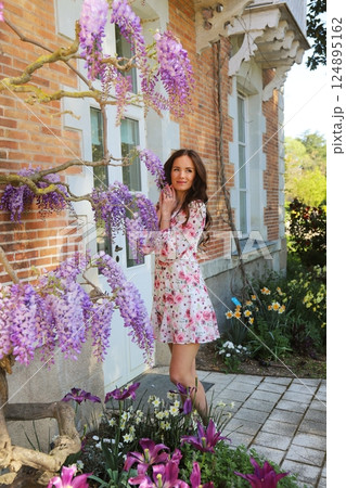 Woman standing by wisteria in spring courtyard 124895162