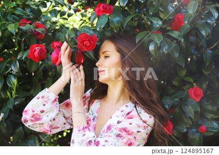 Woman touching red camellias in spring garden Woman touching red camellias in spring garden 124895167