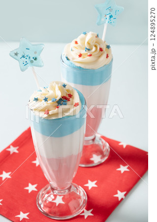 Two layered milkshake or sweet dessert for child on blue background. Food for 4th of July or Memorial Day. Close up. Two layered milkshake or sweet dessert for child on blue background. Food for 4th of July or Memorial Day. Close up. 124895270