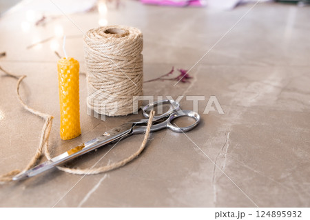 Crafting essentials. Twine, scissors, wax candle on marble surface 124895932