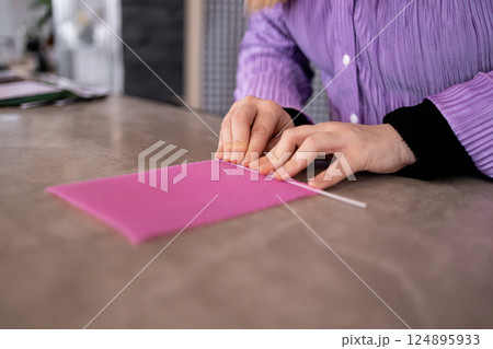Female crafting candle with pink beeswax and wick in workshop 124895933