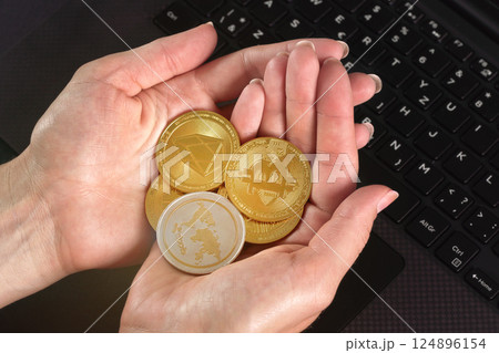 Woman hands holding golden coloured bitcoin, ripple and ethereum cryptocurrency coins over black laptop keyboard Woman hands holding golden coloured bitcoin, ripple and ethereum cryptocurrency coins over black laptop keyboard 124896154