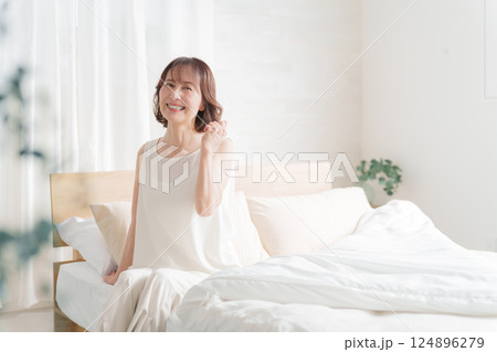 朝ベッドでガッツポーズする中高年女性 124896279