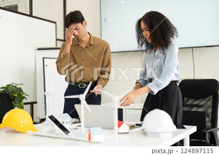 Sustainability and Collaboration. A man and woman in a modern office discussing renewable energy solutions actively. Sustainability and Collaboration. A man and woman in a modern office discussing renewable energy solutions actively. 124897115