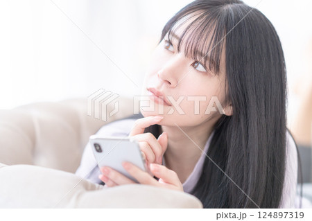 クリニック選びにスマホを使って悩む若い女性 クリニック選びにスマホを使って悩む若い女性 124897319