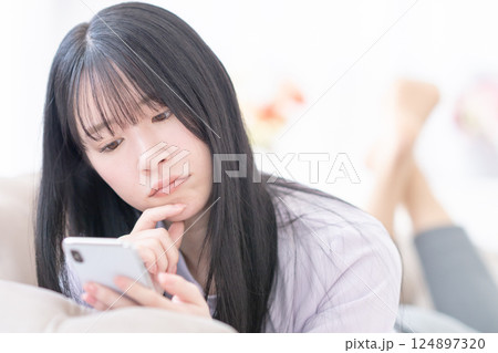 クリニック選びにスマホを使って悩む若い女性 124897320