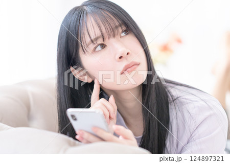 クリニック選びにスマホを使って悩む若い女性 クリニック選びにスマホを使って悩む若い女性 124897321