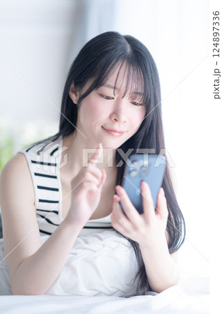 爽やかなタンクトップ姿でスマホを使うナチュラルビューティーのイメージ 124897336