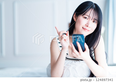 スマホを持っておすすめポーズする若い女性 124897341