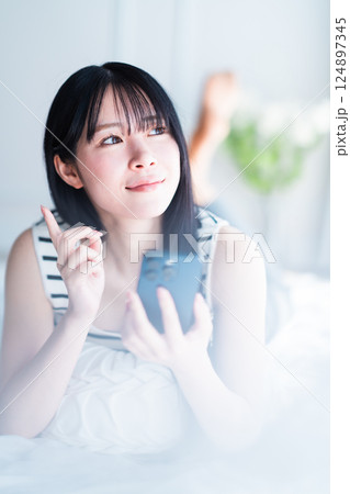 明るい部屋でインターネット検索をする一人暮らしの若い女性 124897345