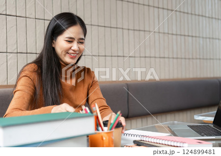 Study Session and Collaboration. A woman smiles while organizing her study materials at a cozy cafe. Study Session and Collaboration. A woman smiles while organizing her study materials at a cozy cafe. 124899481