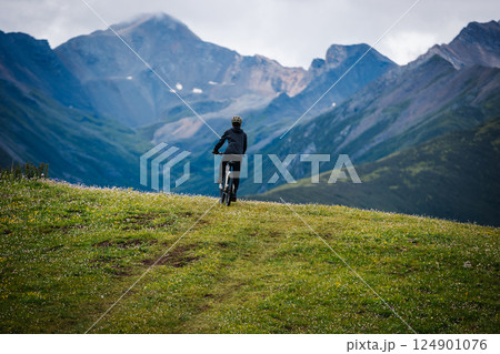 Riding mountain bike on grassland mountain top Riding mountain bike on grassland mountain top 124901076