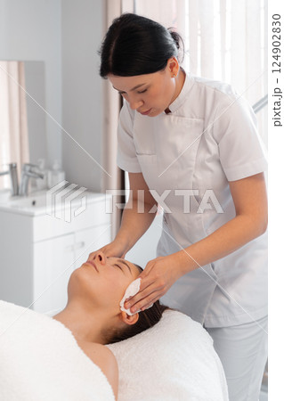 Cosmetologist cleaning woman face in beauty clinic 124902830