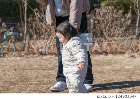 【相模原市立麻溝公園の芝生広場で遊ぶ1歳児とおかあさん】 124903047