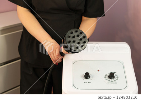 Therapist presenting cavitation handpiece above aesthetic control panel.Keywords: Therapist presenting cavitation handpiece above aesthetic control panel.Keywords: 124903210