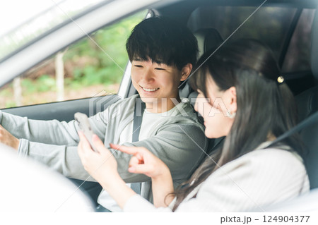 車内でスマホを見ながら会話する若いアジア人カップル,夫婦 車内でスマホを見ながら会話する若いアジア人カップル,夫婦 124904377