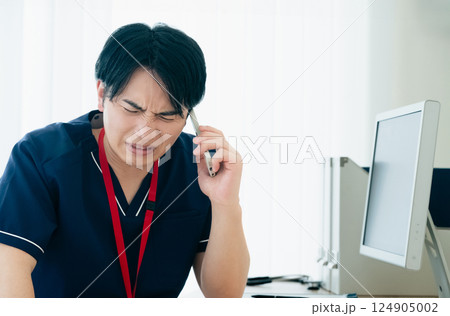 スマホで通話する困った顔の医師 124905002