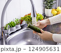 Woman hands washing a cucumber to prepare a fresh salad in the kitchen 124905631