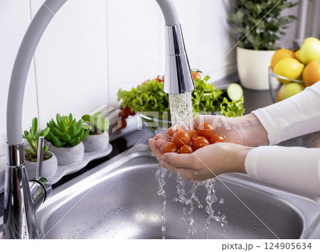 Woman hands washing fresh cherry tomatoes to prepare a fresh salad 124905634