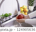 Woman hands washing fresh red apple in the kitchen 124905636