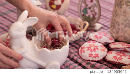Easter eggs and quail eggs being placed in ceramic rabbit holder during festive spring celebration 124905643