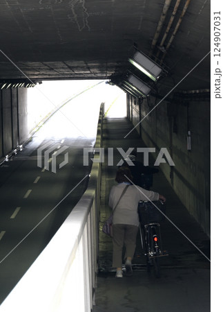 アンダーパスの歩道を自転車をおして歩く歩行者 アンダーパスの歩道を自転車をおして歩く歩行者 124907031