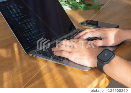 ノートパソコンでプログラミングする手元　スマートウォッチとIT作業風景 124908239