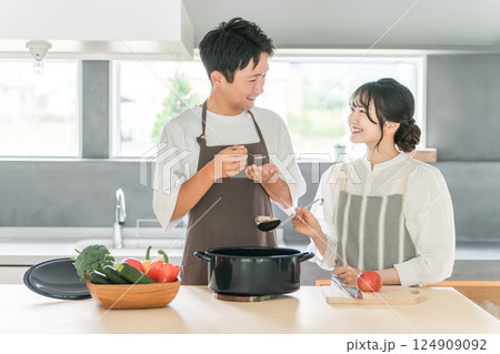 料理を作って味見をする夫婦・カップル・男女(キッチン) 料理を作って味見をする夫婦・カップル・男女(キッチン) 124909092