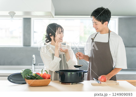 料理を作って味見をする夫婦・カップル・男女（キッチン） 124909093
