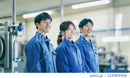 作業服を着た東洋人の男女が室内で笑顔で並んで立っている様子 124909489