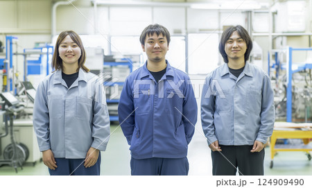 作業服を着た東洋人の男女が室内で笑顔で並んで立っている様子 124909490