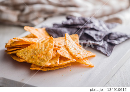Dark and yellow nachos chips on kitchen table. 124910615