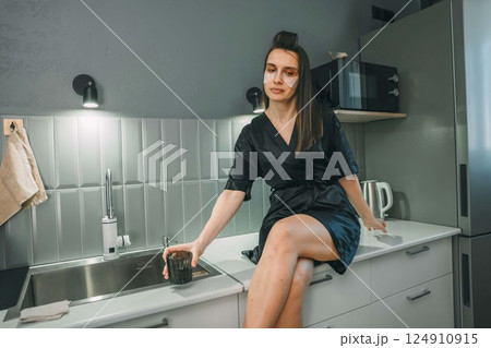 young woman hydrating with glass of water in a contemporary kitchen, concept of health and hydration 124910915