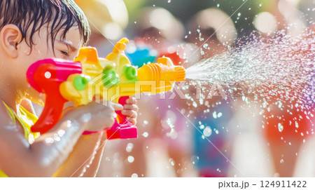 Children with Water toy spraying brightly colored stream in sunny outdoor setting 124911422