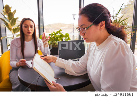 Two professional Caucasian women discussing business plans in a cafe during lunch break. Concept of productivity and collaborative online marketing. Mid shot 124911661