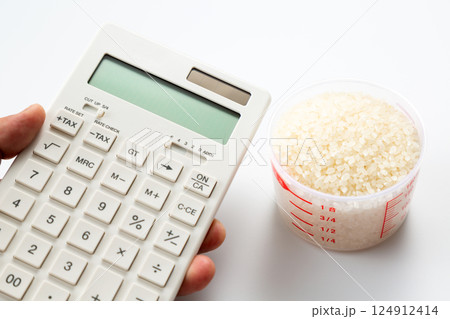 計量カップに入った米と電卓を持つ手元 124912414