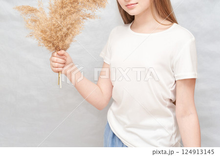 Young caucasian female holding dried pampas grass in casual white t-shirt 124913145