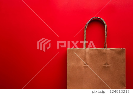 Brown paper bag is sitting on a red wall. 124913215