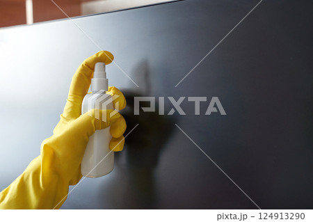 Gloved hand cleaning screen with spray bottle for hygiene and maintenance 124913290