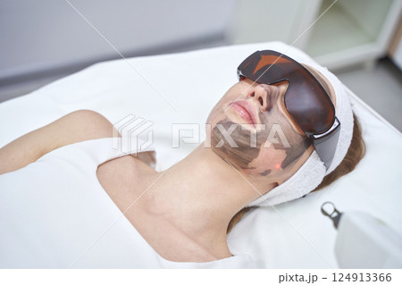 Female adult receiving carbon laser facial treatment in spa setting Female adult receiving carbon laser facial treatment in spa setting 124913366