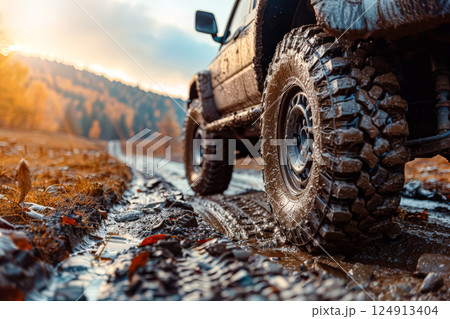 Dirty truck with mud on the tires is driving down a dirt road 124913404