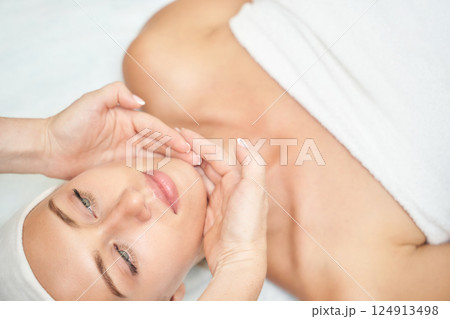 Female caucasian adult relaxing during spa facial treatment with gentle massage Female caucasian adult relaxing during spa facial treatment with gentle massage 124913498